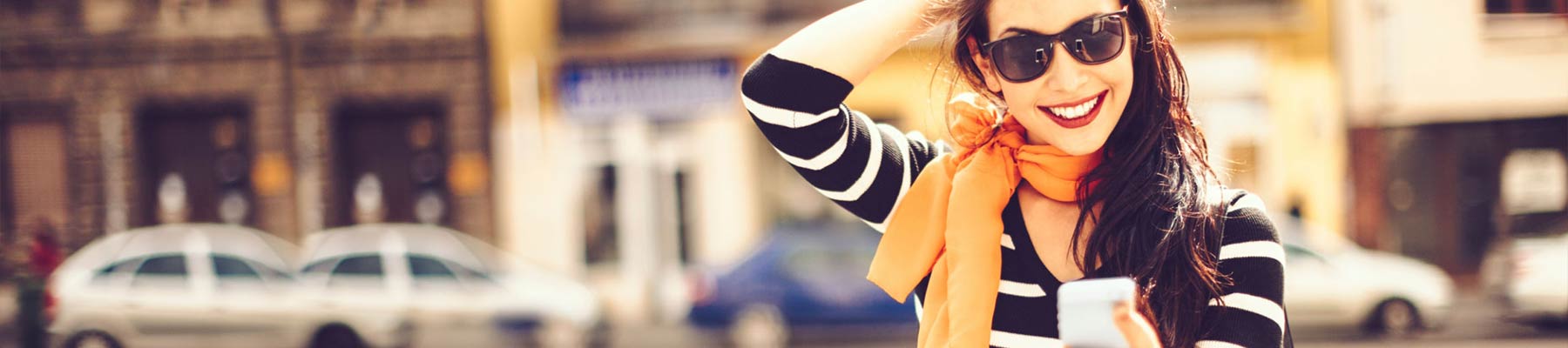 Person with an orange scarf smiling and checking their phone.