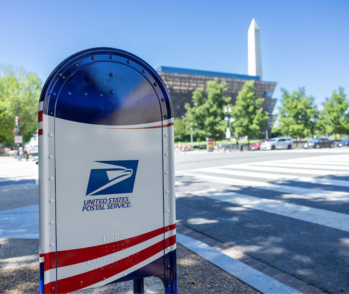A collection box wrapped in a red, white, and blue design featuring the Freedom 250 logo, with the US Capitol building in the background.