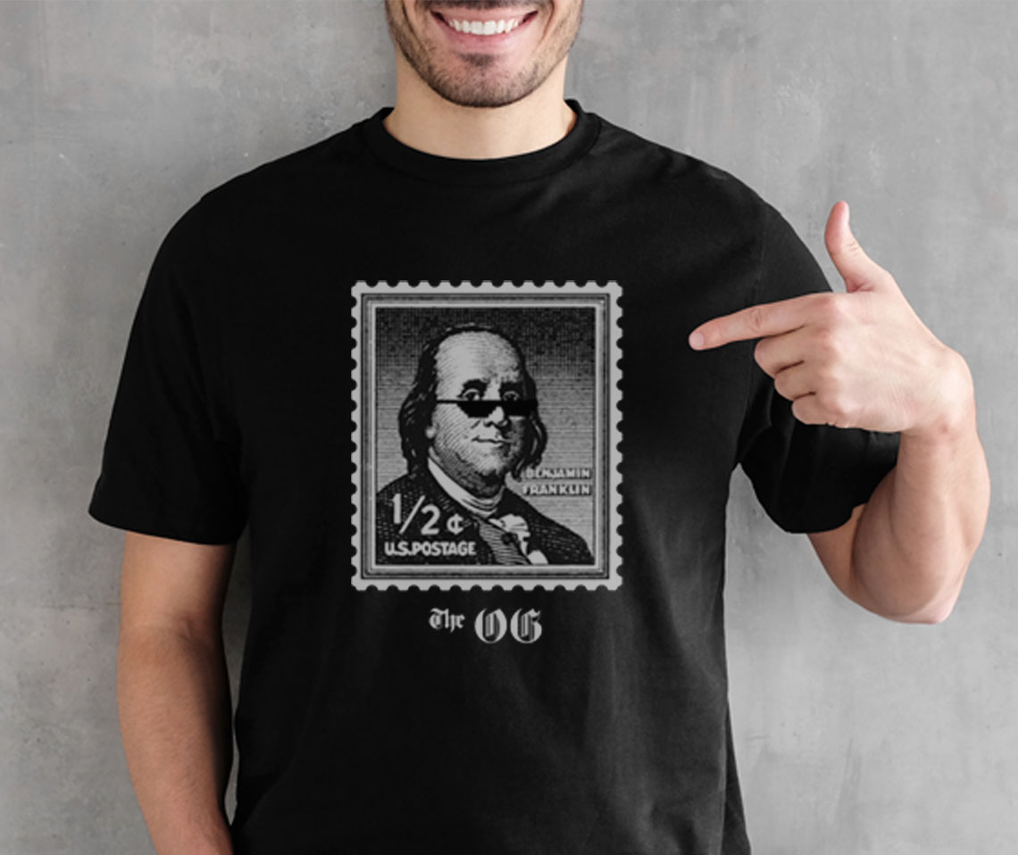 Man wearing a Benjamin Franklin stamp t-shirt and pointing at the design.